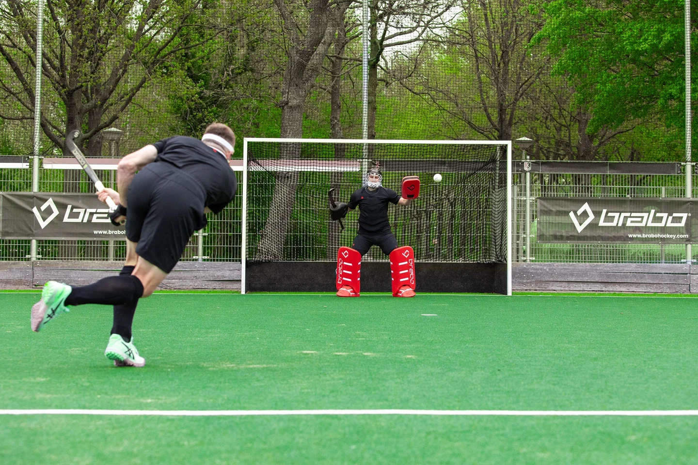 Hockeyspeler en Brabo-keeper tijdens een schot op doel